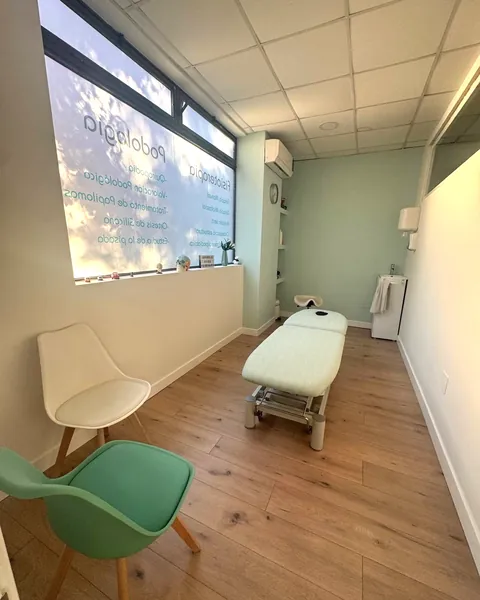 Consulta de podología de la Clínica Paula Vega en Leganés, con camilla y la ventana rotulada con los servicios