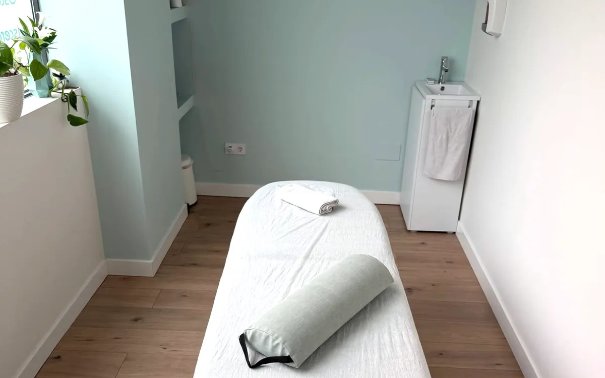 Sala de tratamiento de la Clínica Paula Vega en Leganés, con camilla, paredes verde agua y lavabo
