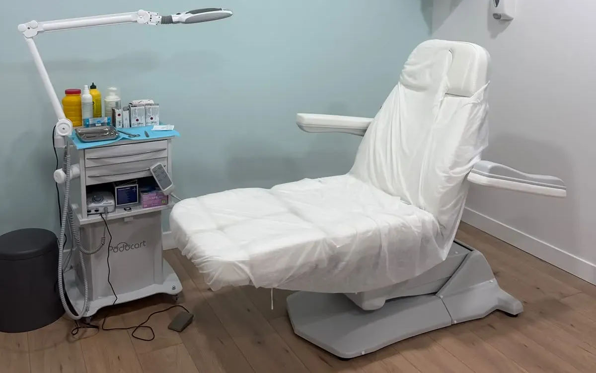 Consulta de podología de la Clínica Paula Vega en Leganés, con el sillón de podología, el carro de instrumental y la lámpara de lupa