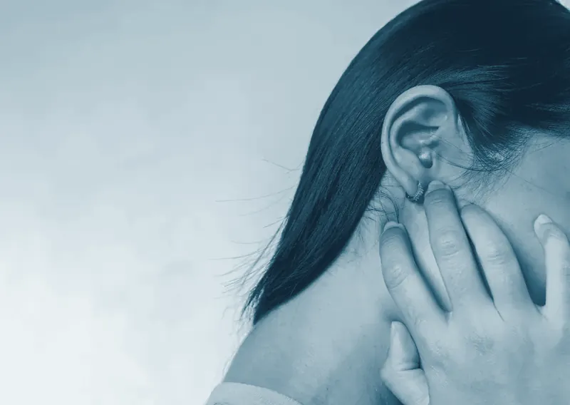 Mujer con la mano en el oído y la zona de la oreja y la mandíbula marcada en rojo