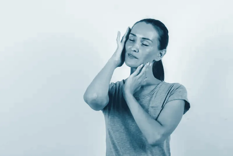 Mujer con gesto de dolor tocándose la mandíbula y la sien