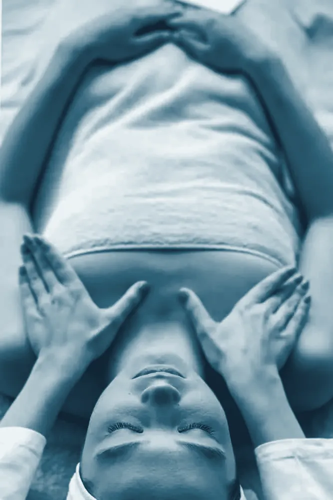 Fisioterapeuta con las manos sobre el pecho de una paciente tumbada: liberación miofascial