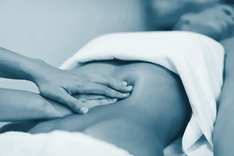 Manos de fisioterapeuta sobre el abdomen de una paciente cubierta con una toalla