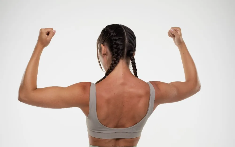 Mujer de espaldas contrayendo la musculatura de la espalda y los brazos tras un trabajo de fuerza